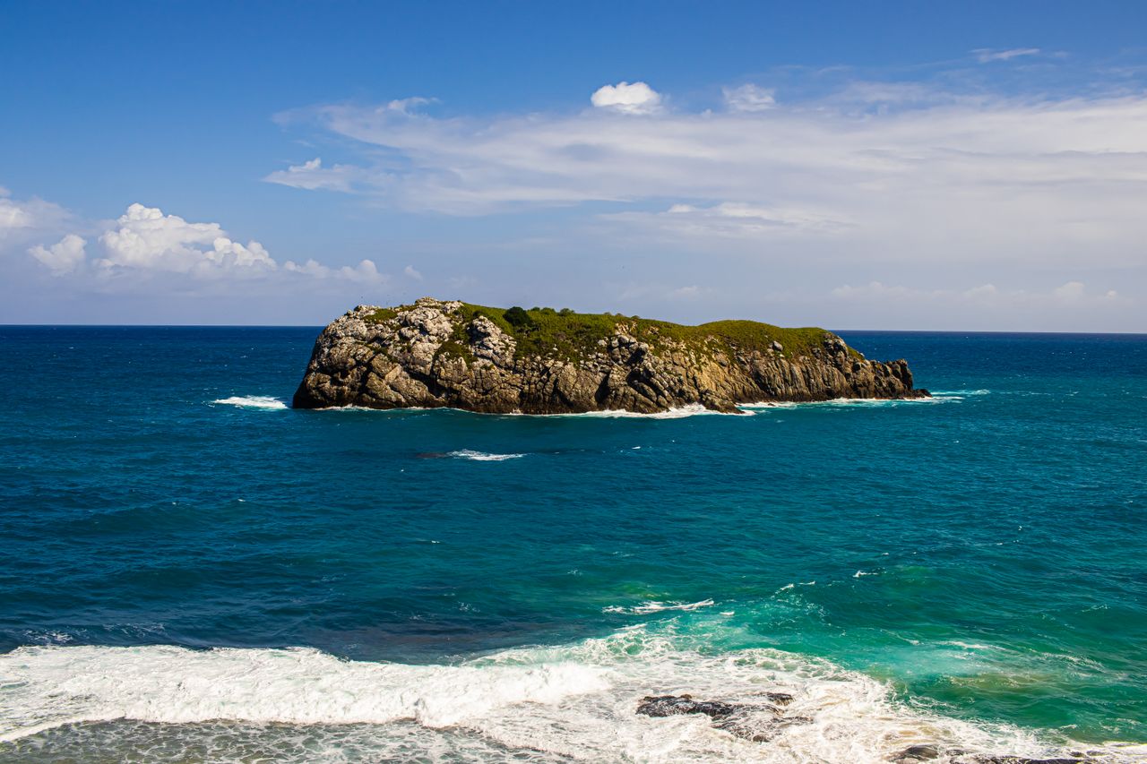 captivating view of a rocky island surrounded by the vibrant blue ocea