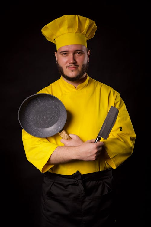 A man in a chef's uniform holding a frying pan