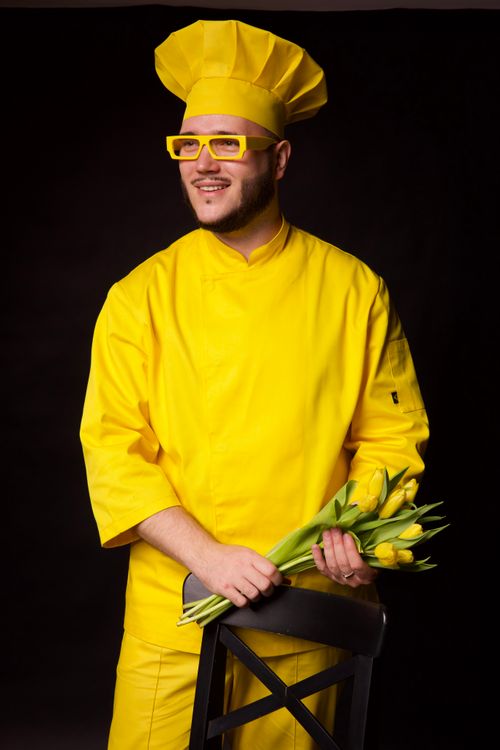 Free Chef wearing yellow attire and glasses poses with tulips against a black background. Stock Photo