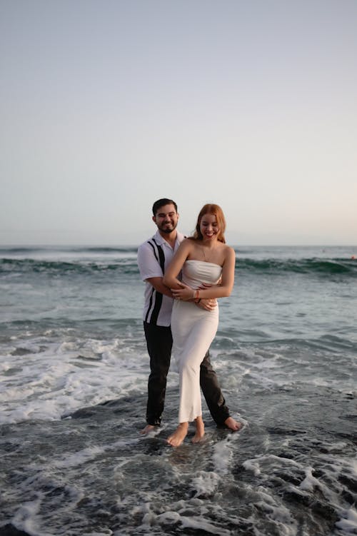 A bride and groom standing in the ocean