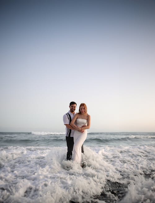A bride and groom standing in the ocean