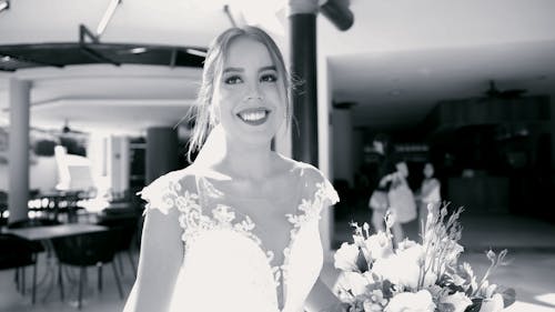 A bride is smiling while holding a bouquet