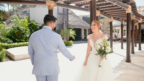 A bride and groom walk under an arbor
