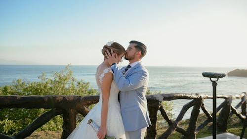 A bride and groom kiss at the beach