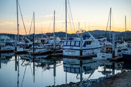 Free Peaceful sunset view of sailboats moored at a marina, reflecting in calm waters. Stock Photo