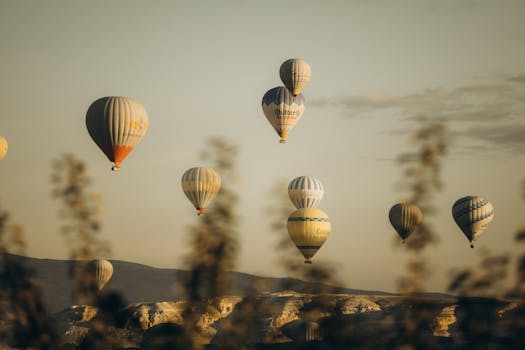 Hot air balloons float over Cappadocia's unique landscape at sunrise, offering a serene and breathtaking view.