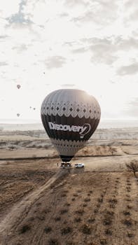 A hot air balloon floats over Cappadocia's unique landscape during sunrise, capturing a serene aerial view.