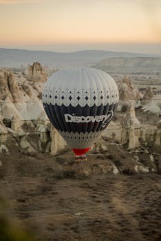 A beautiful hot air balloon floats over Cappadocia's unique rock formations at sunrise.