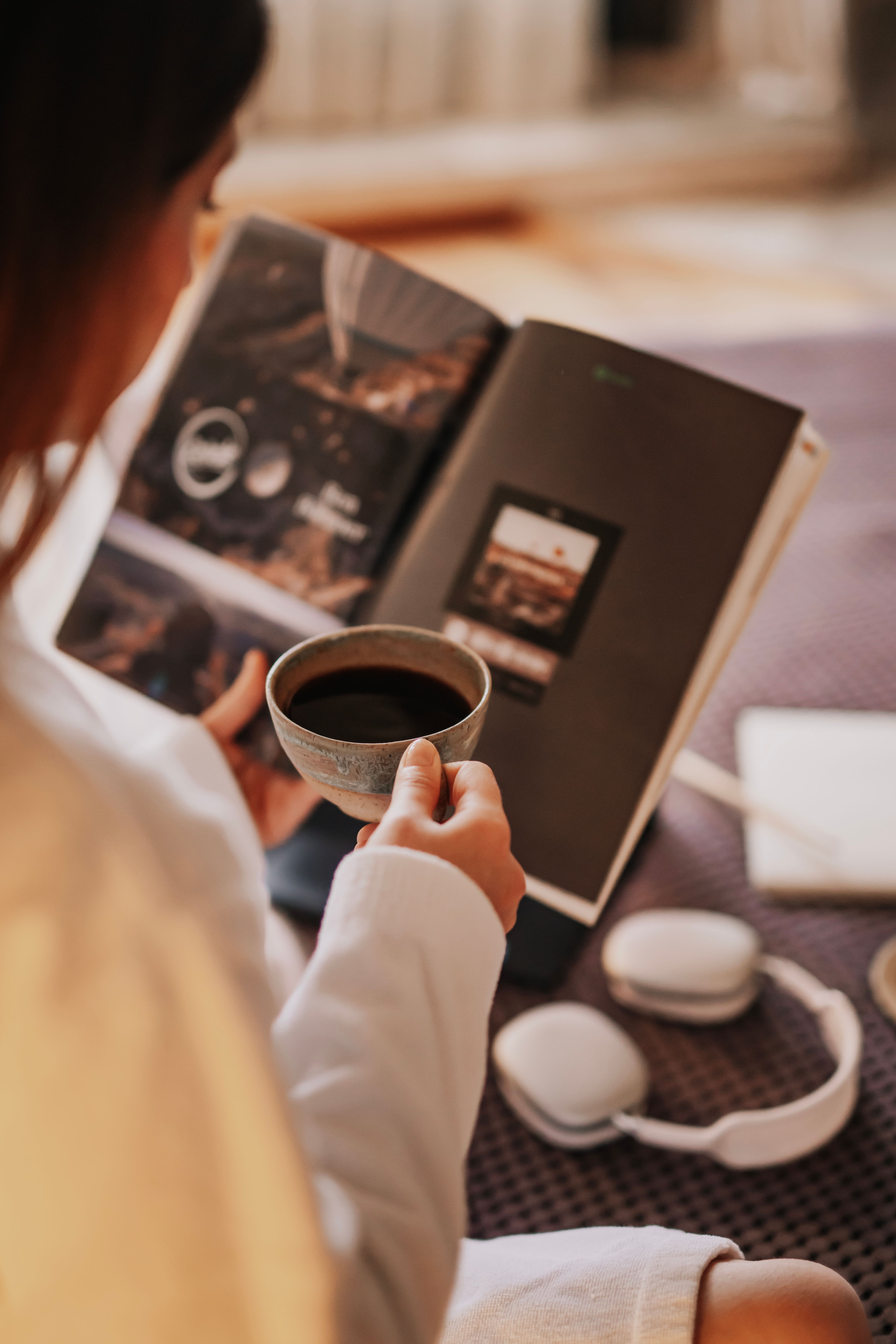 Woman enjoying coffee and reading in a cozy indoor setting.