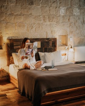 Woman relaxing in a cozy hotel room in Ürgüp, Türkiye, reading a magazine in the morning light.