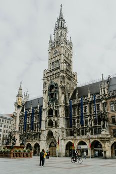 Historic Gothic-style New Town Hall at Marienplatz in Munich with tourists and cyclists.