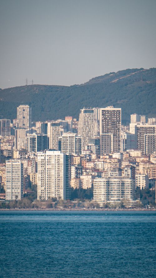 Free Skyline of a modern city with skyscrapers near the coast and mountains in the background. Stock Photo