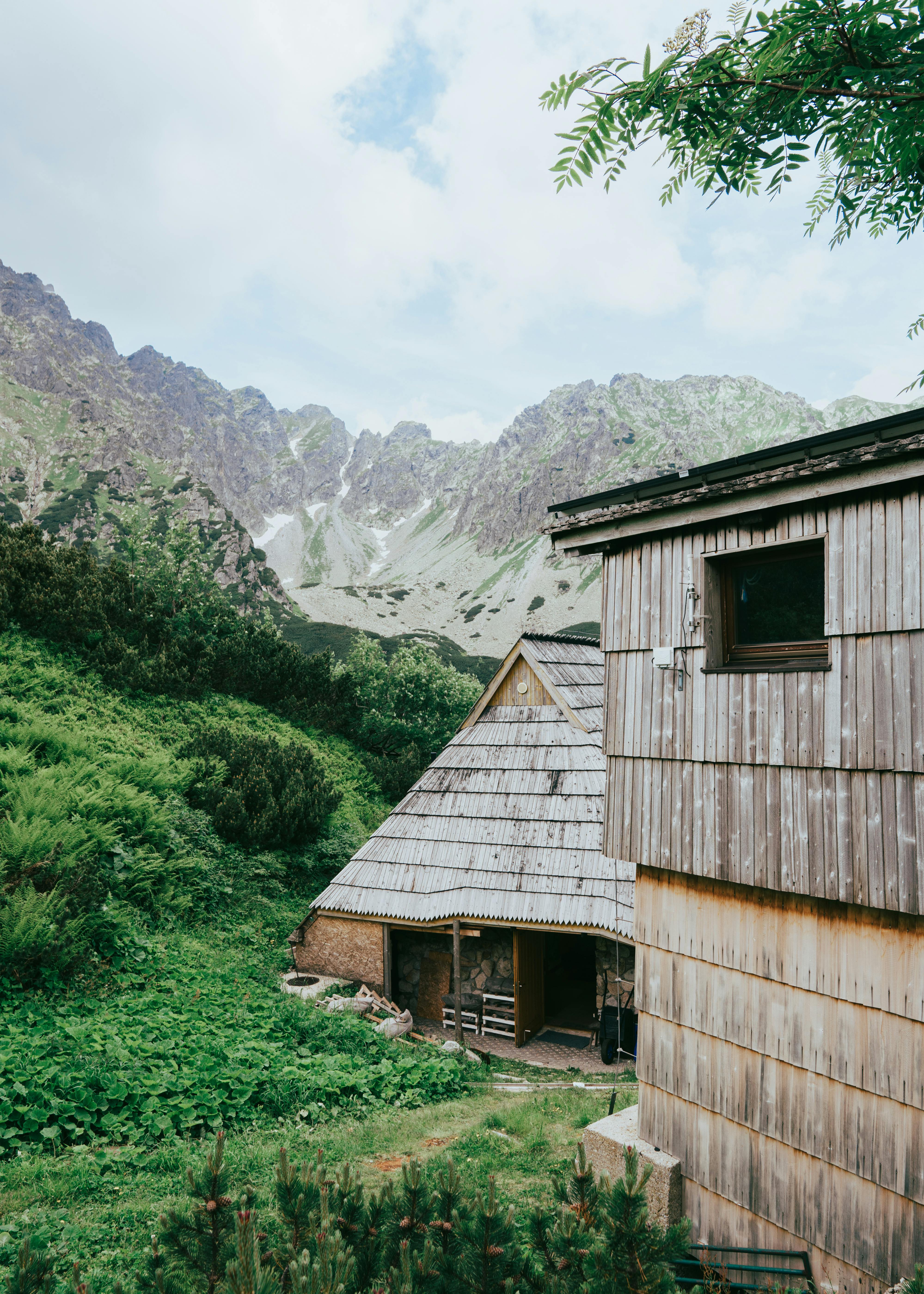 Charming wooden shelters tucked in the lush Tatra mountain landscape under a bright sky.