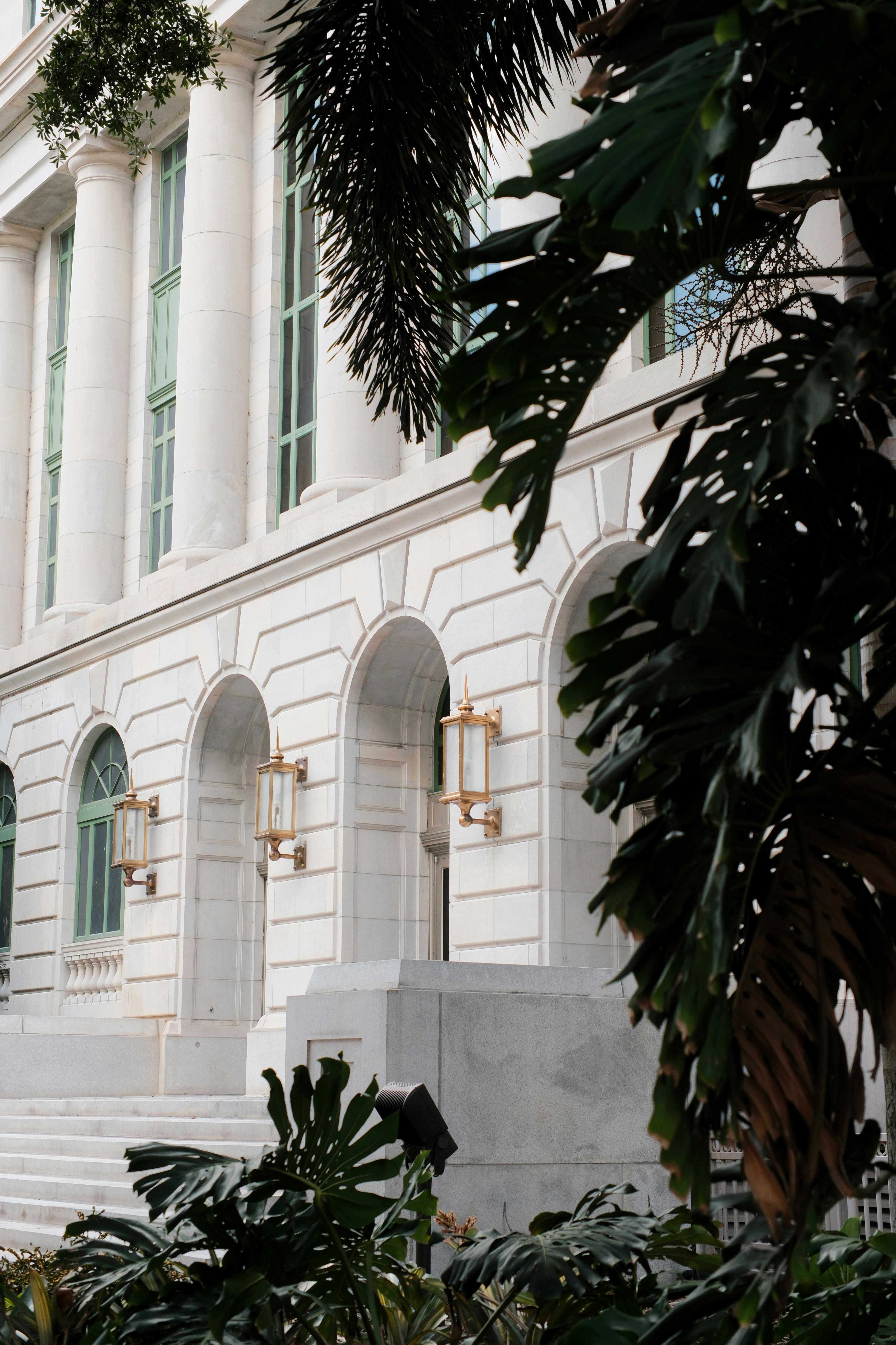 Elegant neoclassical building facade with arches and greenery.