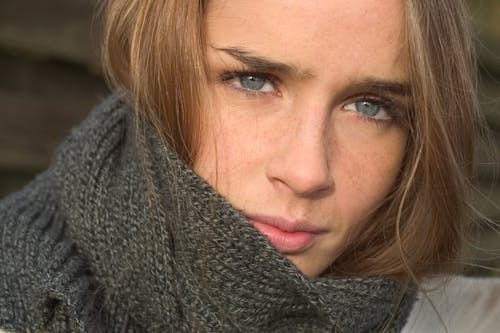 Close-up photo of a brown haired woman wearing a grey  scarf