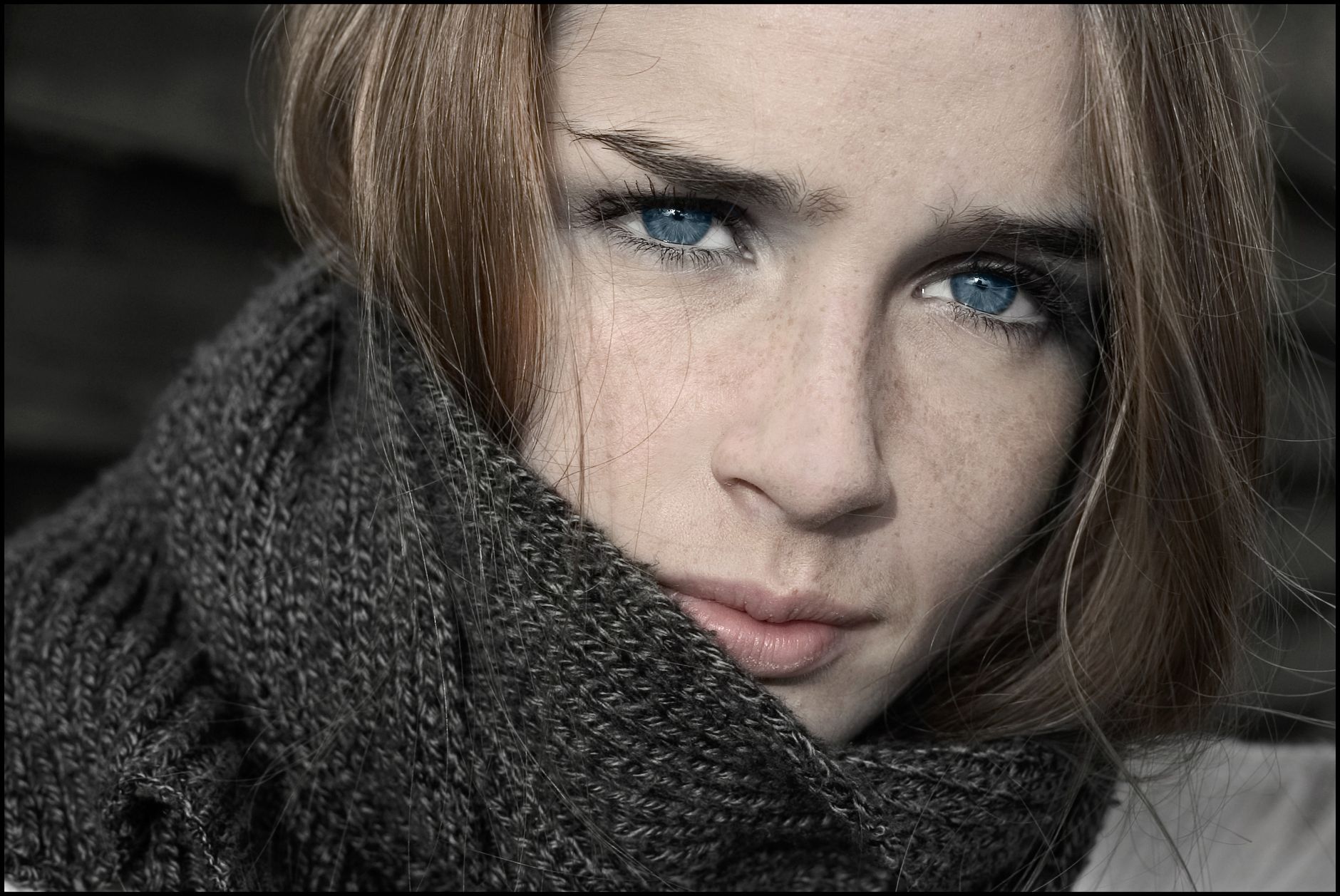 Intimate close-up portrait of a woman with striking blue eyes wearing a scarf.