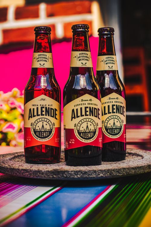 Free Three Allende IPA bottles arranged on a colorful table setting, showcasing Mexican craftsmanship. Stock Photo