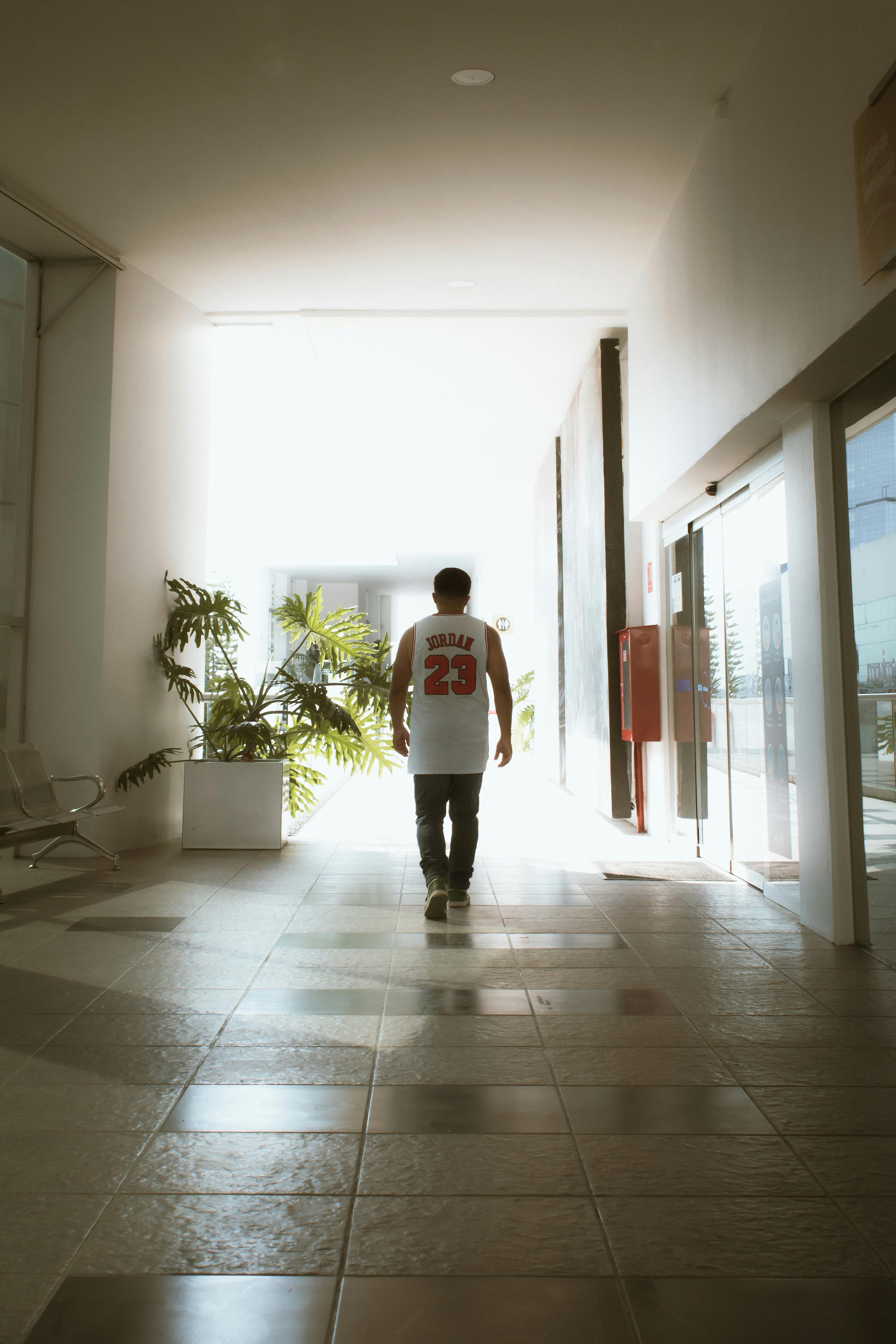 back view of man walking in building wearing basketball jersey shirt