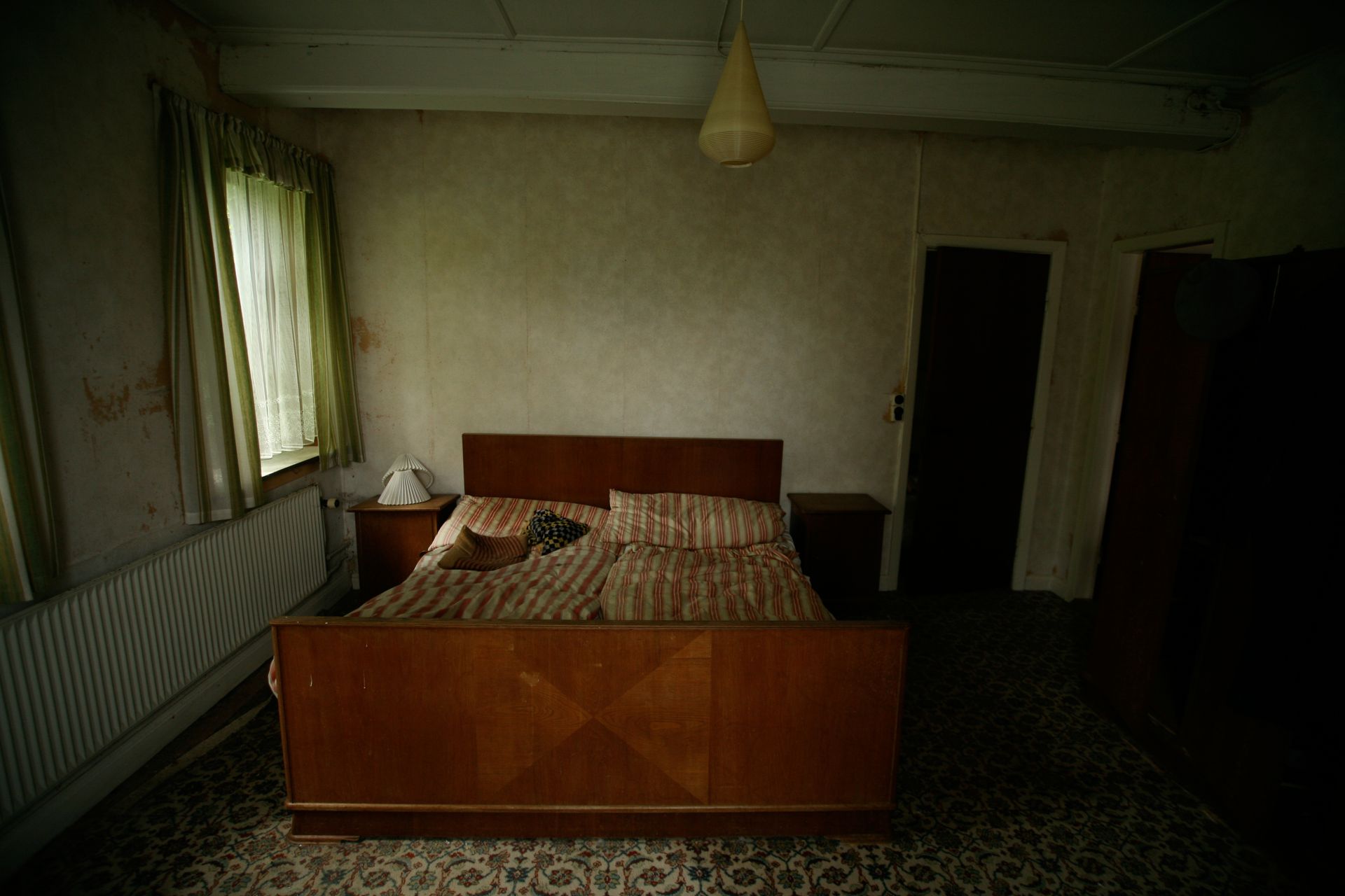 A cozy vintage bedroom with classic wooden furniture and muted wallpaper design.