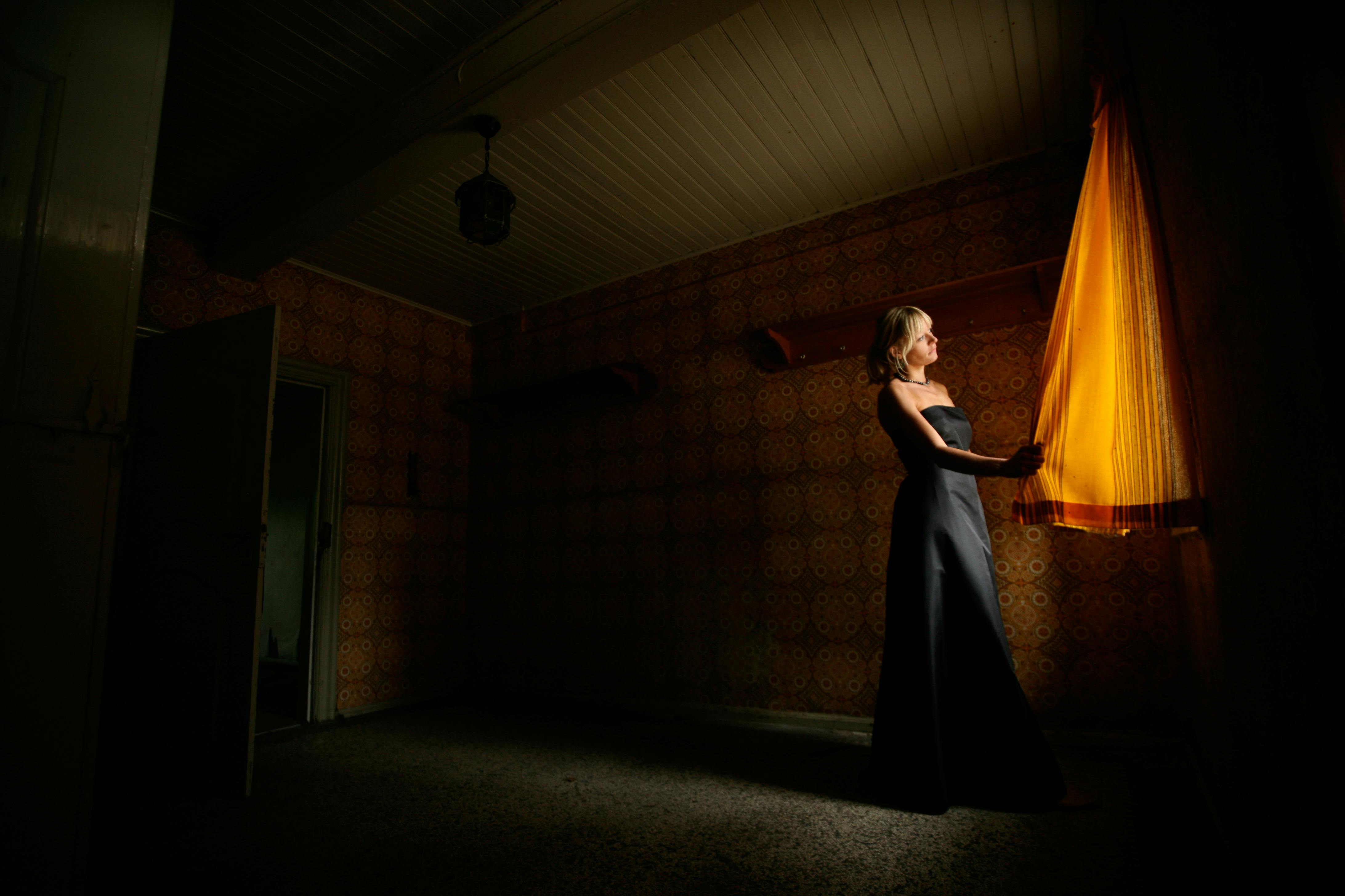 photo of a woman holding orange curtain in a room