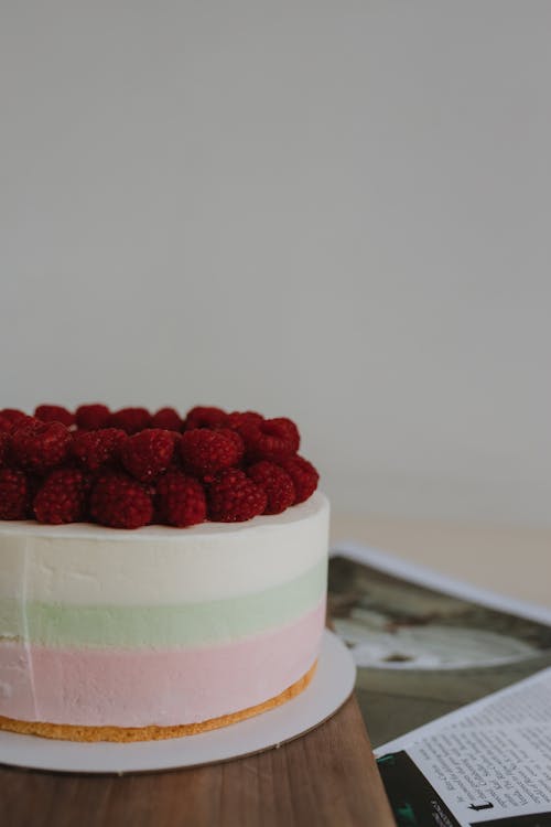 A cake with raspberries on top is on a table