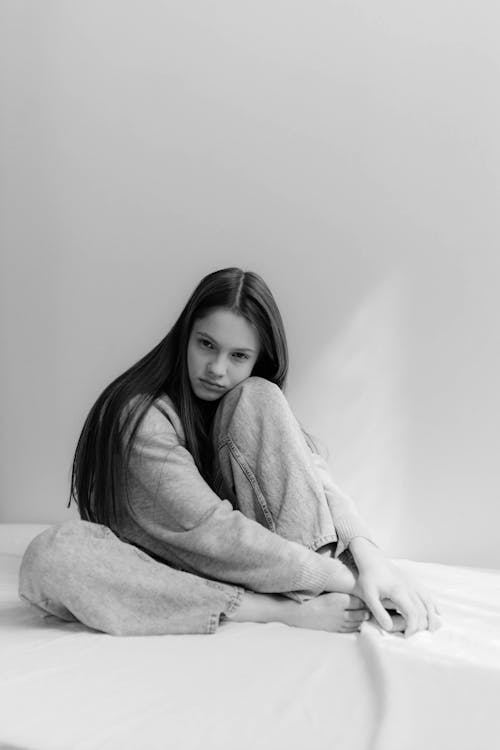 A woman sitting on a bed in black and white