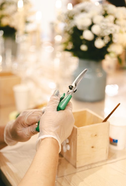 A woman in gloves holding a pair of scissors