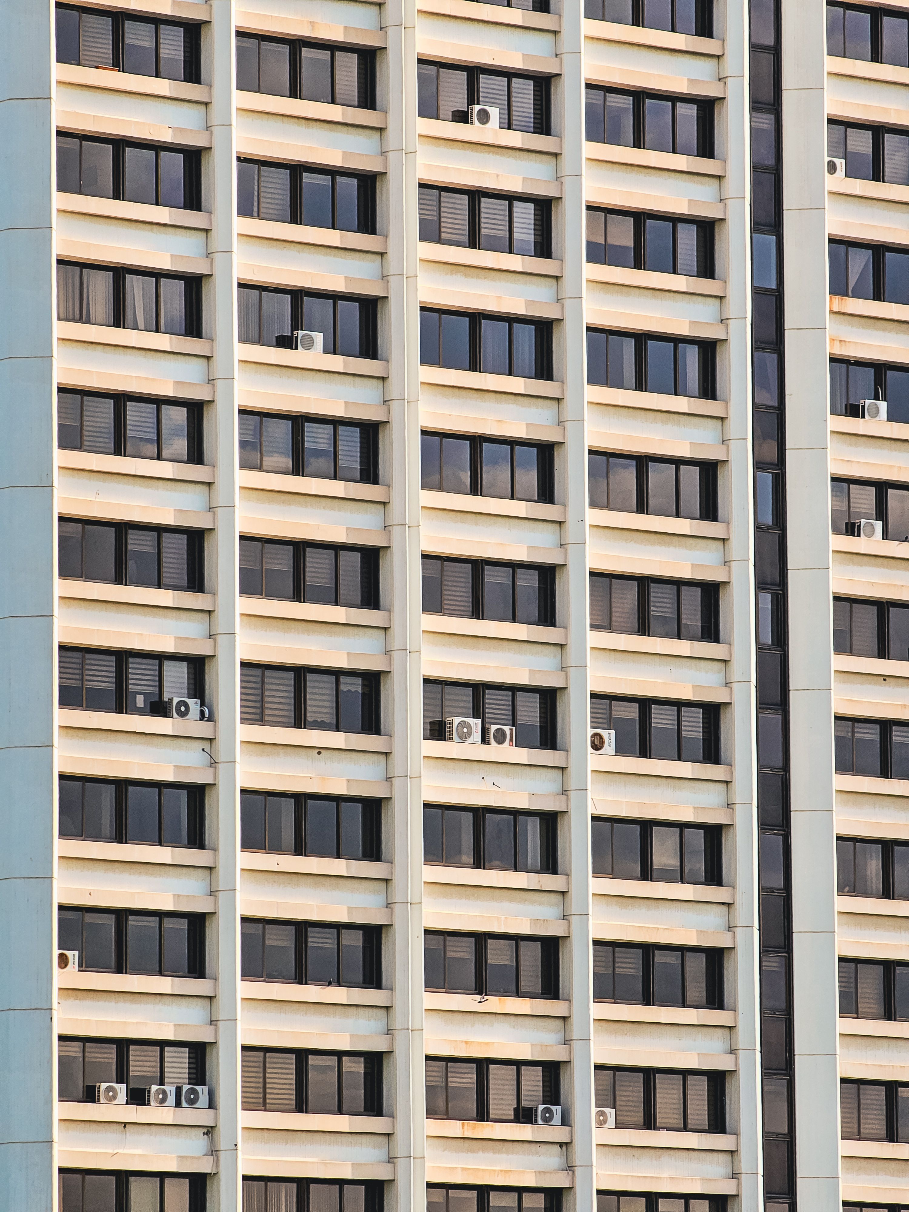 Symmetrical view of an apartment building facade with multiple windows and AC units.