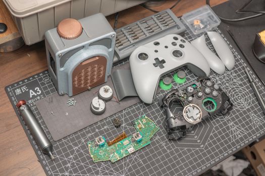 A disassembled video game controller and components set on a desk mat, illustrating electronics repair.