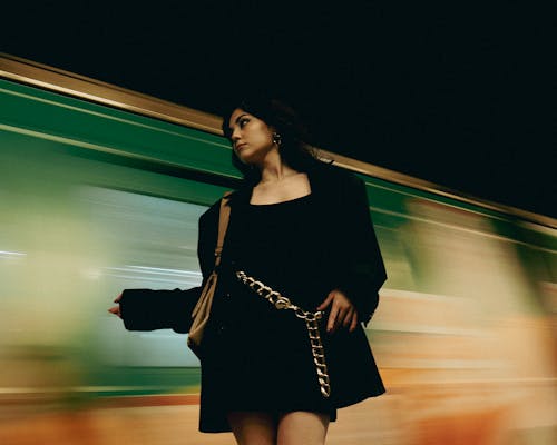 A woman in black dress standing next to a train