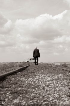 A man walks alone on railway tracks, symbolizing solitude and adventure.