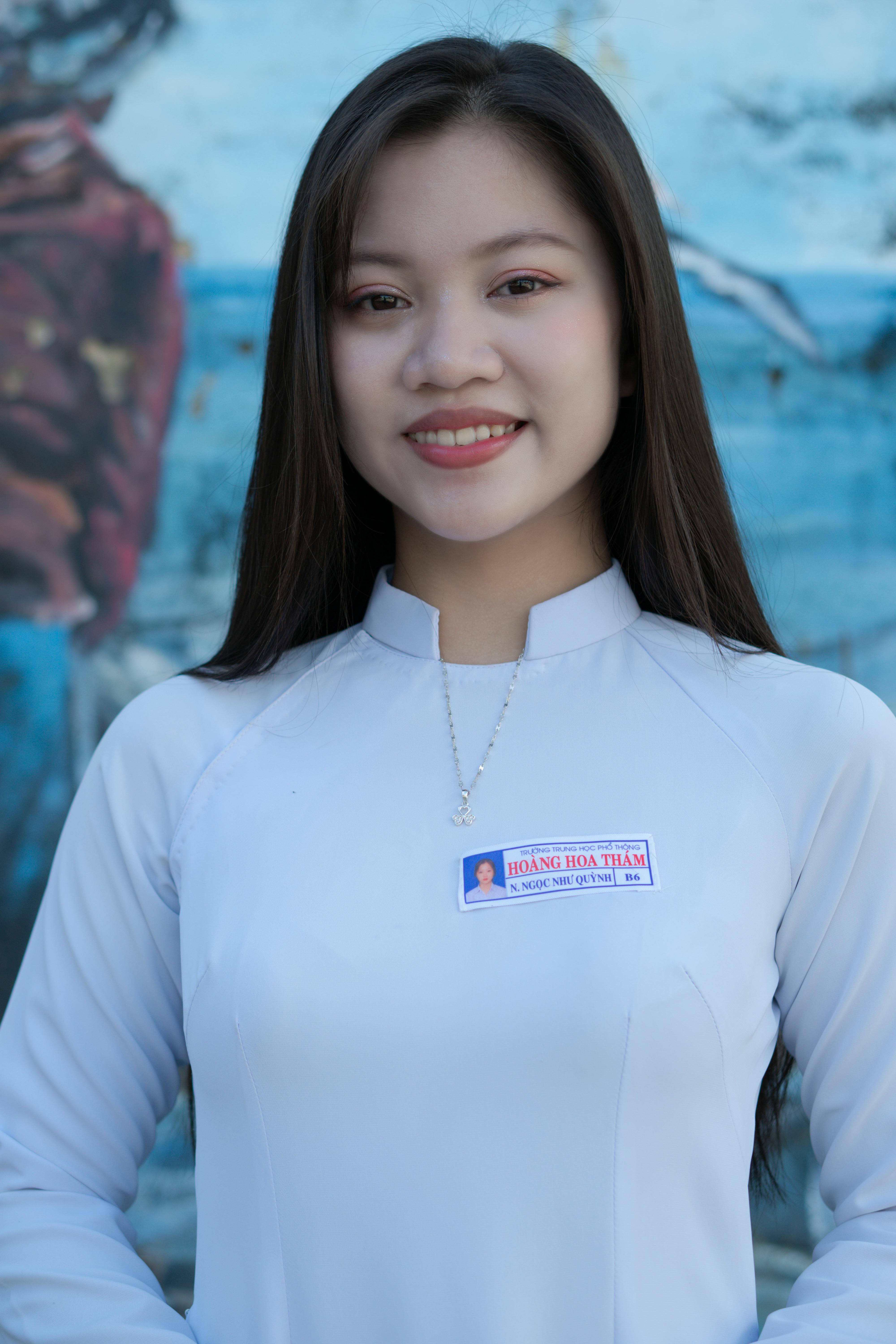Portrait of a smiling woman wearing a white tunic with a serene blue background.