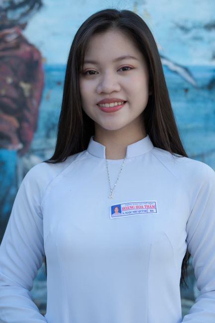 Portrait of a smiling woman wearing a white tunic with a serene blue background.
