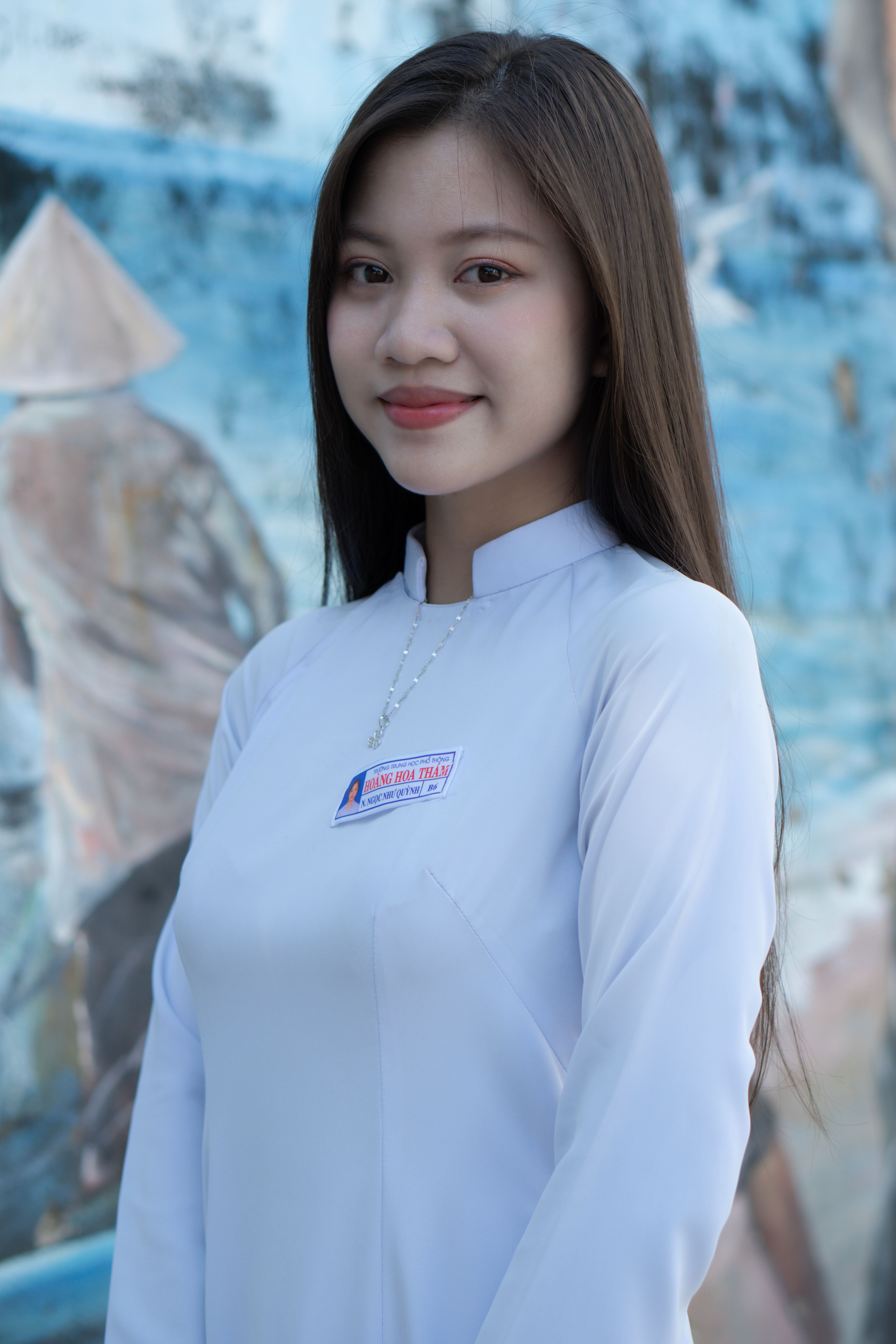 Elegant portrait of a woman in traditional Asian attire against a blurred outdoor backdrop.