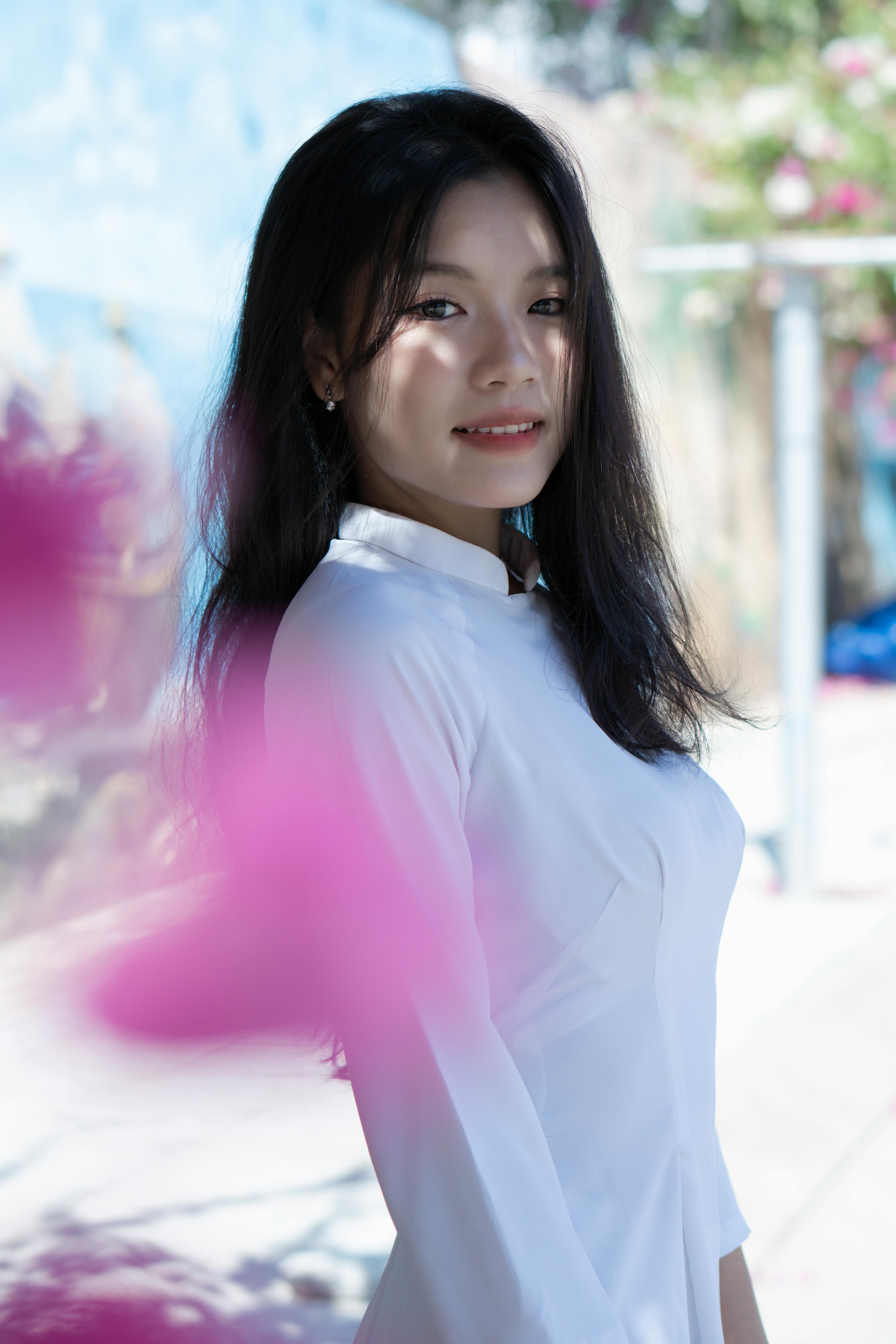 Portrait of an elegant Asian woman in a white traditional dress with natural surroundings.