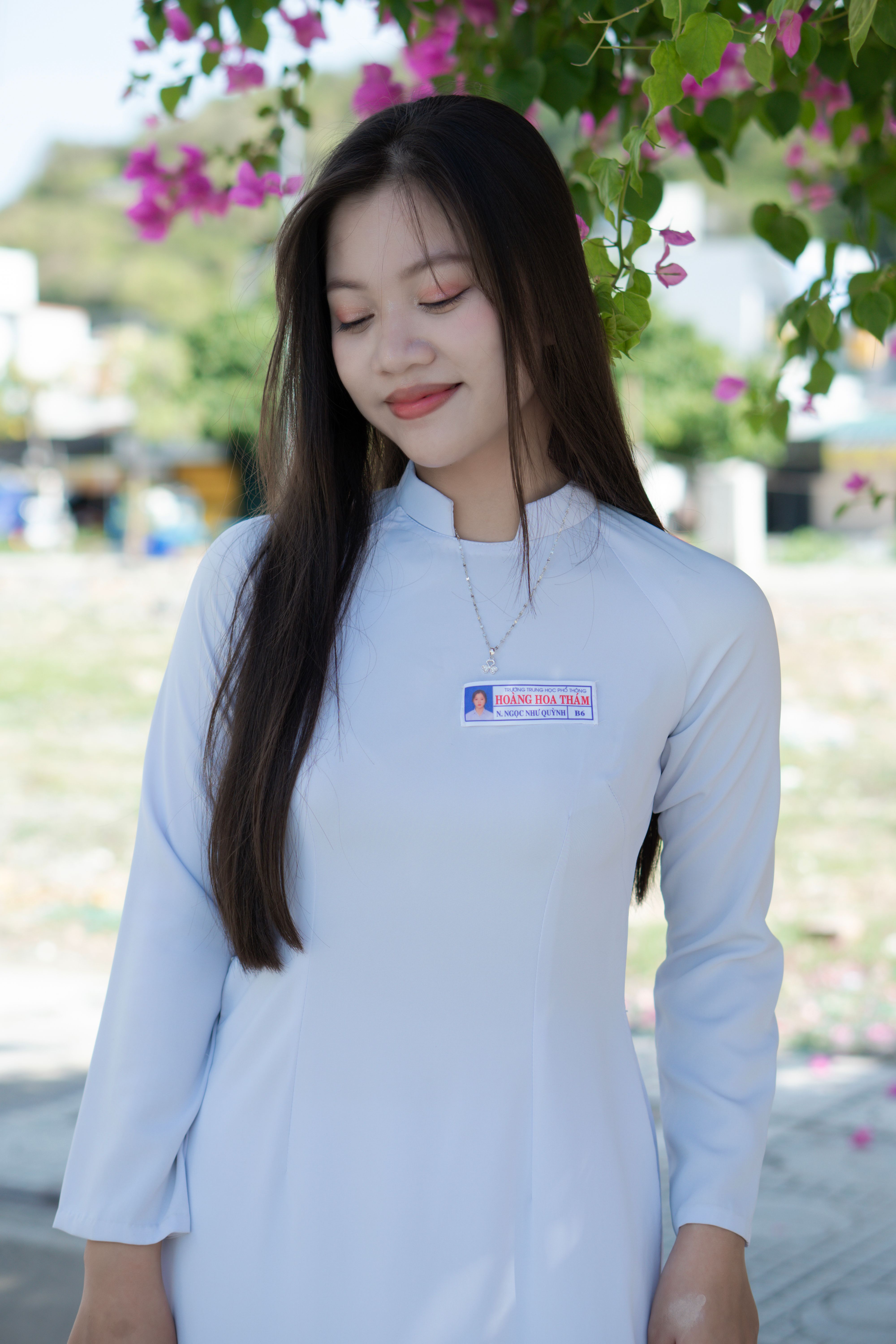 Asian woman smiling in a white traditional dress with long hair and flowers.