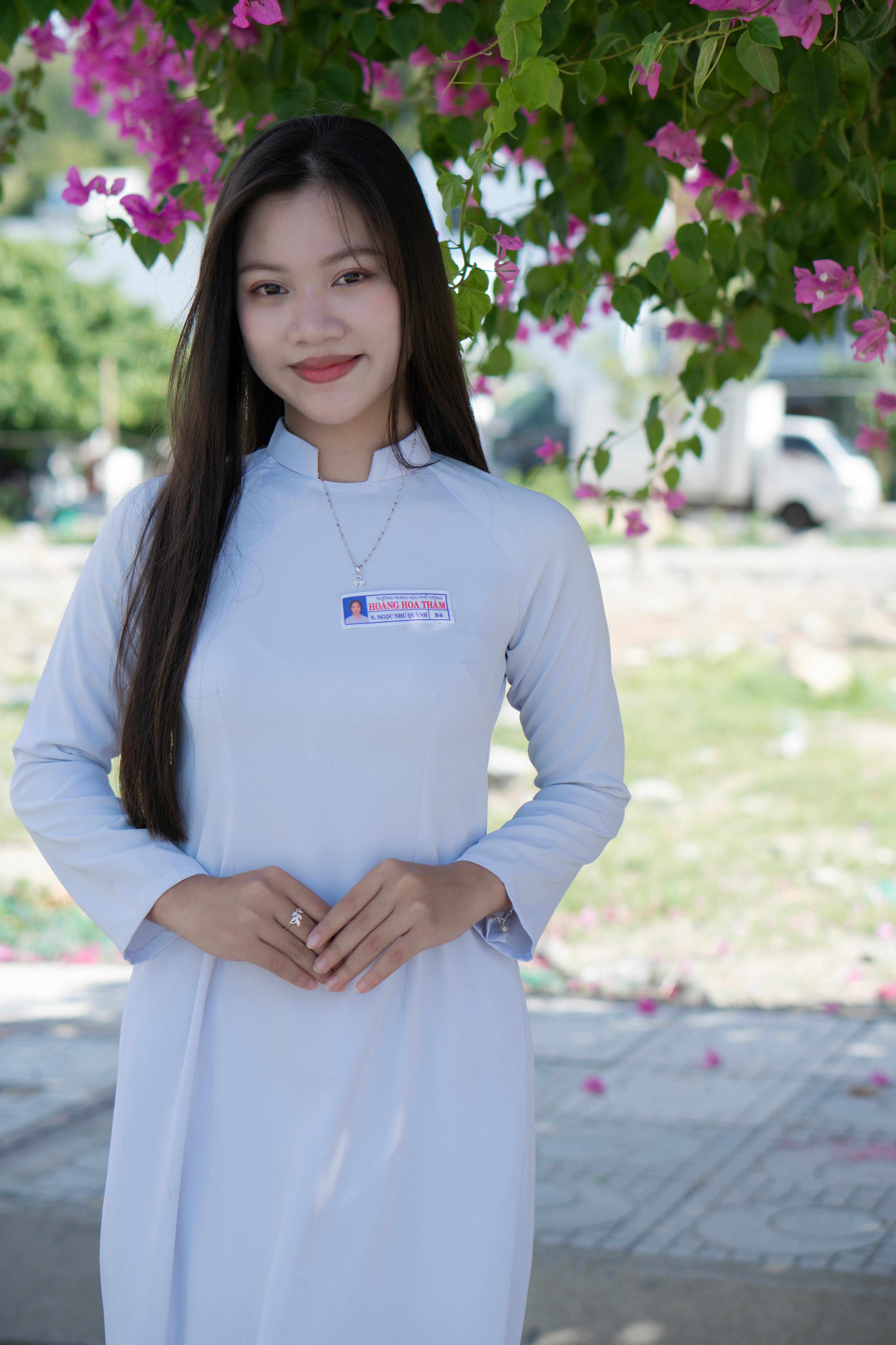 Portrait of a smiling woman in traditional dress with flowers in a sunny outdoor setting.