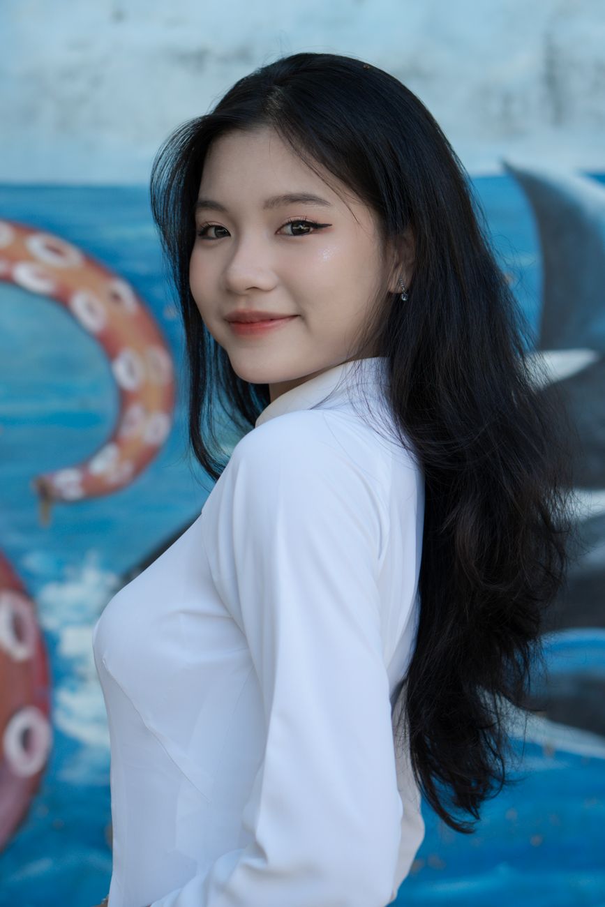 Portrait of a young Vietnamese woman smiling in a traditional ao dai.