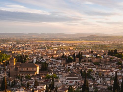 Free Explore the stunning aerial view of Granada, Spain, with historic buildings and lush greenery at sunset. Stock Photo