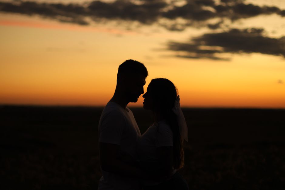 Silhouette of a couple embracing at sunset, evoking romance and unity.