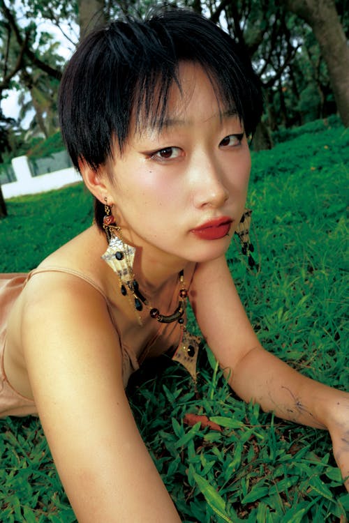 A woman laying on the grass with earrings