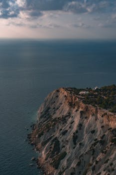 Stunning sunset view over the rugged cliffs and ocean surrounding Ibiza, Spain. by Kevin Kobal