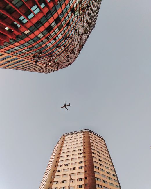 Dynamic view of an airplane flying high over city skyscrapers, showcasing urban architecture.