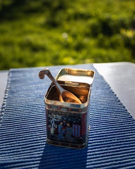 一个老式的咖啡罐，放在户外的蓝色纹理垫子上，旁边有一把木勺