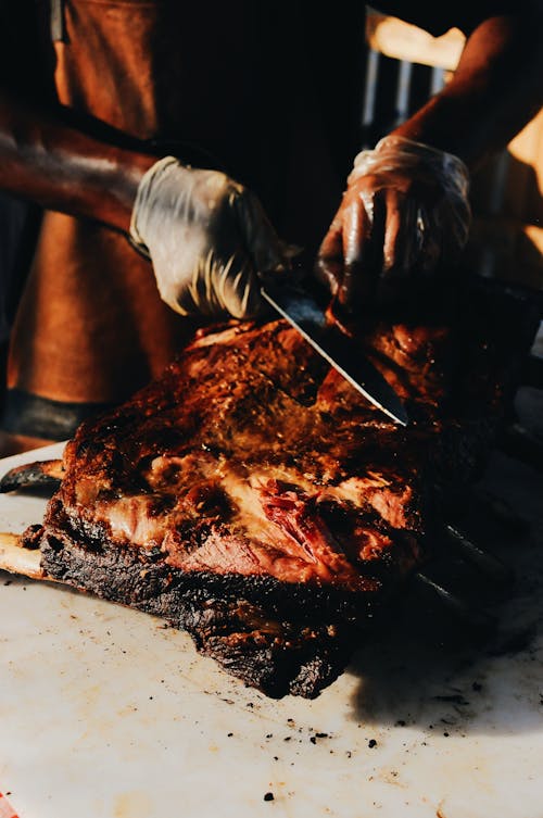 Close up Photo of a Person Wearing Hand Gloves  Cutting Roasted Meat