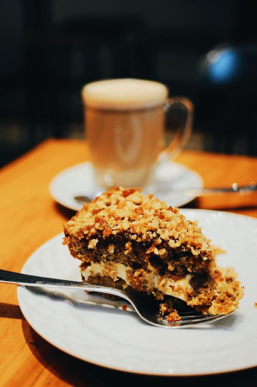Free Close-up of a slice of cake with nuts and creamy layers served with coffee, perfect for a cozy morning. Stock Photo