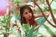 一位时尚女性在户外摆姿势，四周环绕着树叶，尽显风姿与美丽