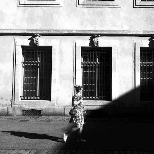 A woman walking down the street in front of a building