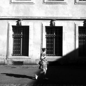 Woman walking past a shuttered facade — photo by Alexis B on Pexels