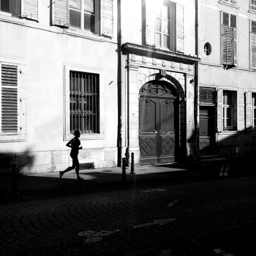 A person is running down the street in front of a building